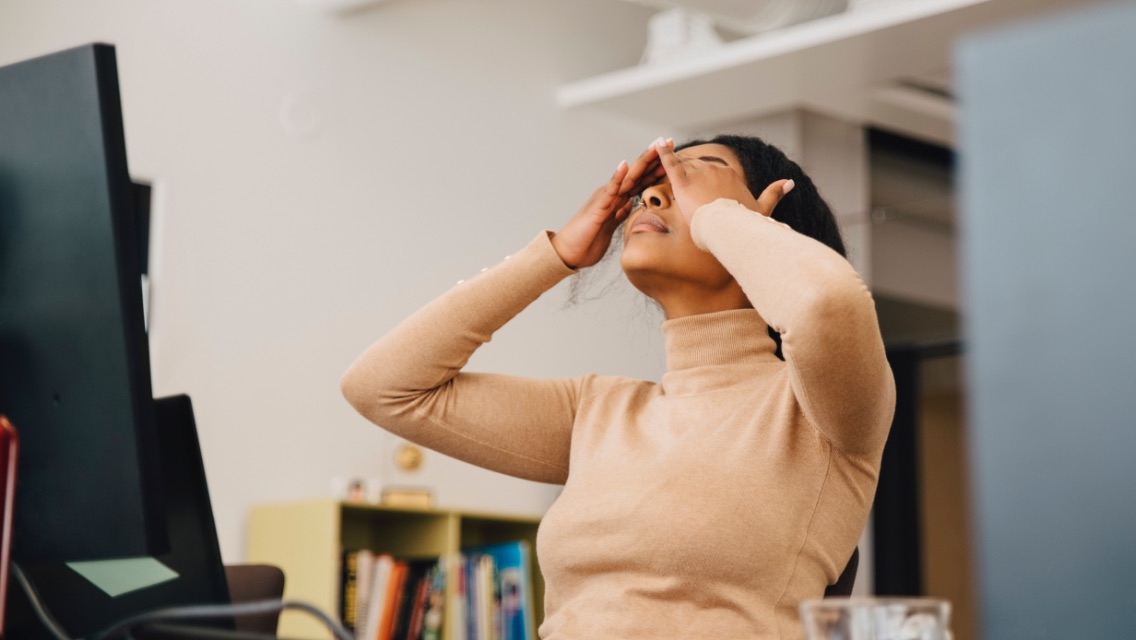 A woman rubbing her eyes, stressed while at work.