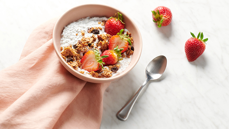 a bowl of chia seeds pudding topped with granola and strawberries