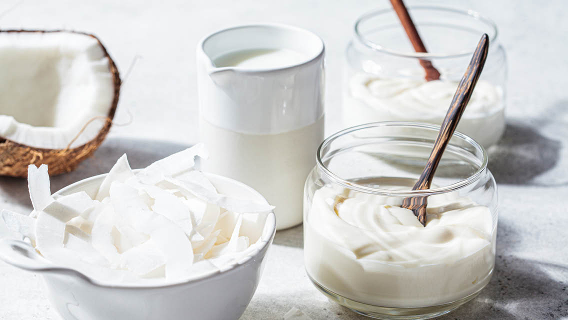 coconut flakes and a variety of non-dairy products in clear containers with wooden spoons
