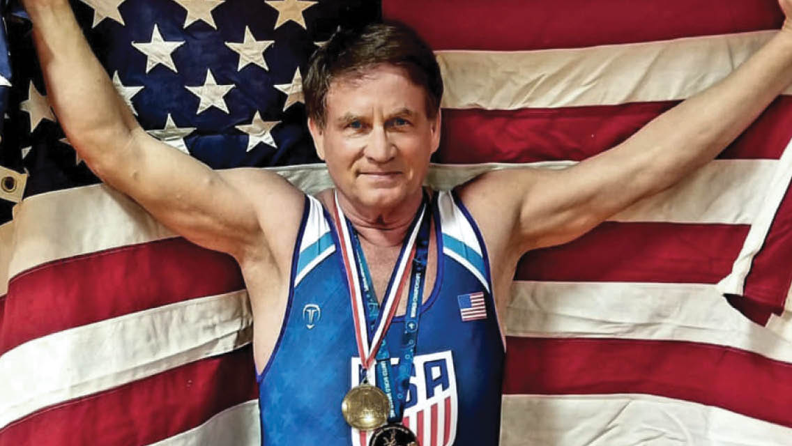 Dean Barnard with his wrestling medals holding an American Flag