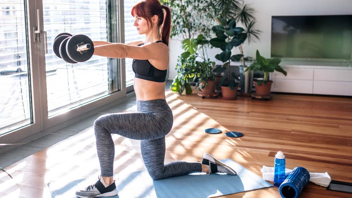 A woman lifting weights at home.