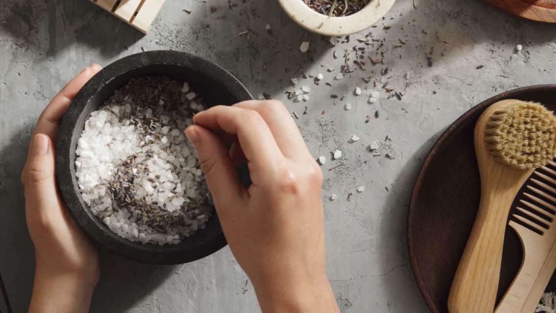hands reach into a bowl filled with sea salt
