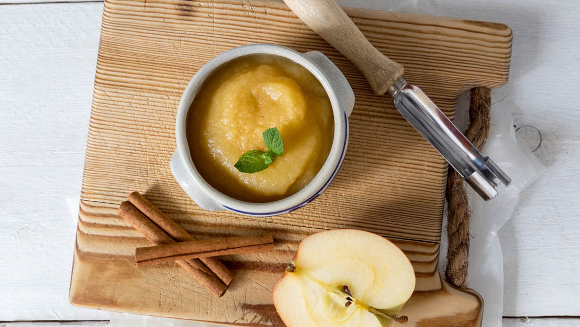 a bowl of apple sauce on a rustic cutting board