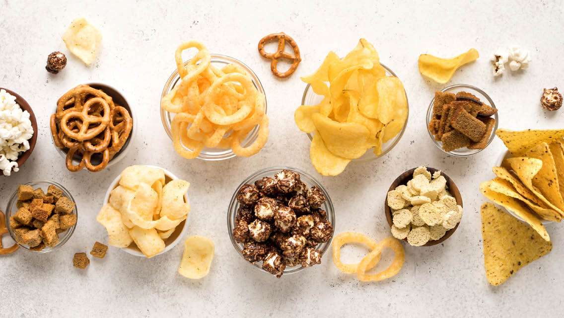 bowls filled with chips, popcorn, pretzels and other processed junk foods