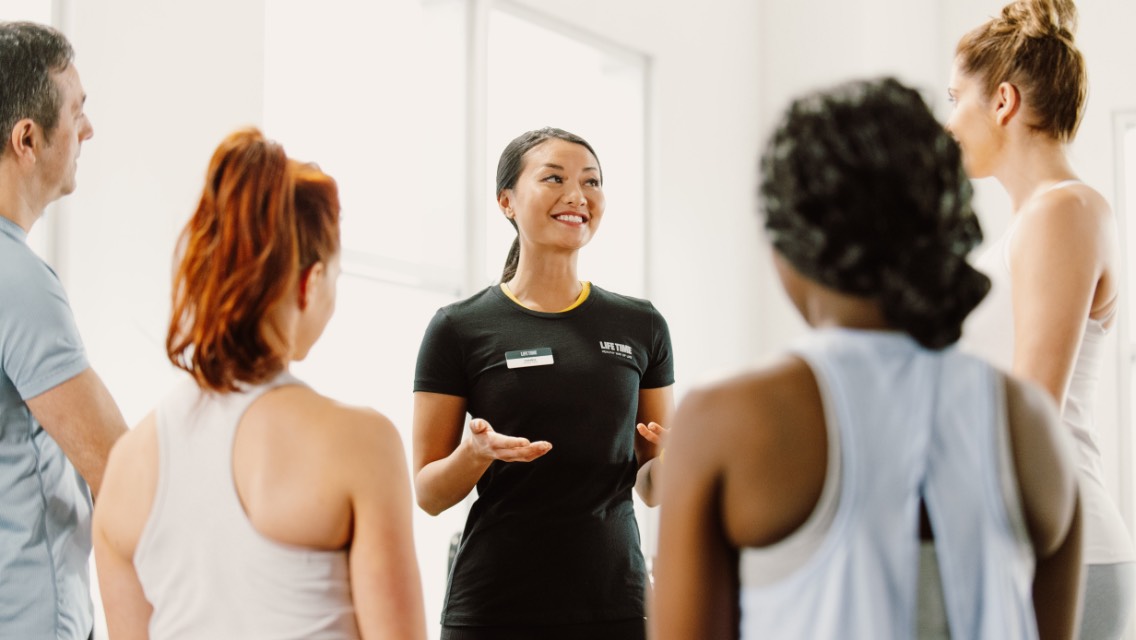 A Life Time fitness professional speaking with four members in workout wear.