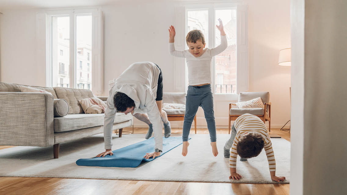 a dad and two kids work out in their living room