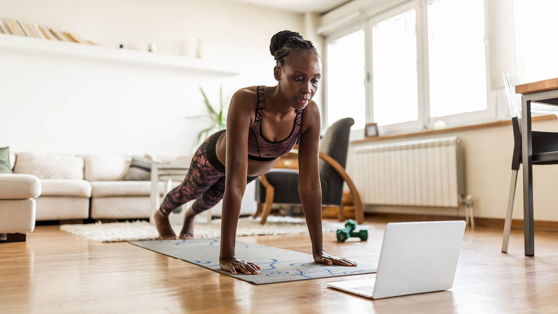 a woman holds a plank position in her home