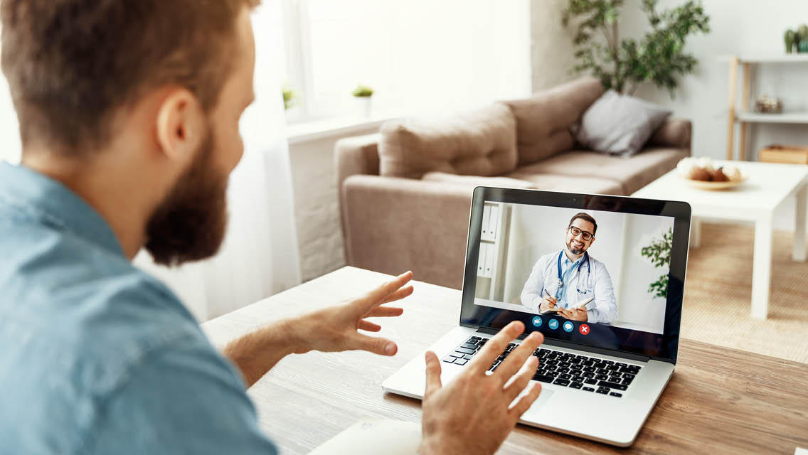 a man talks to his doctor through a computer at home