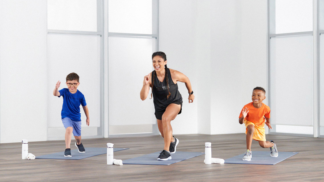 An adult woman instructor and two kids doing the Kids Studio SHRED class.