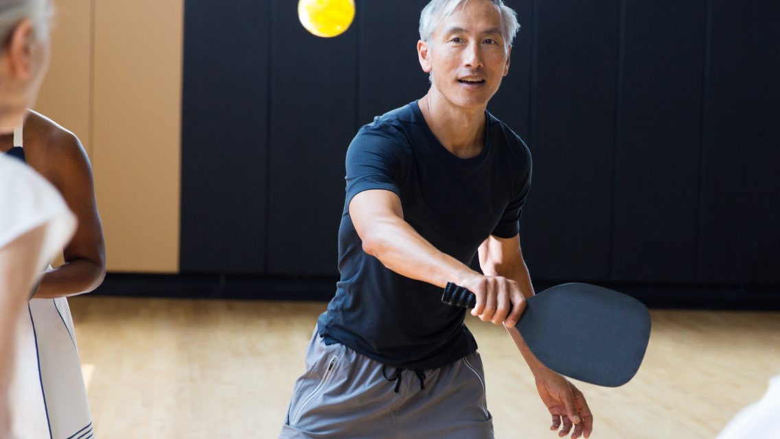 An adult man playing a game of pickleball at Life Time.