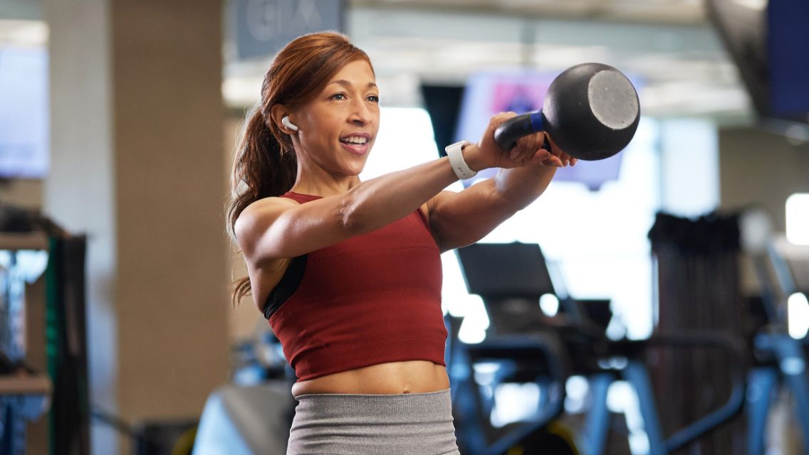 A woman in a health club doing a kettlebell swing.