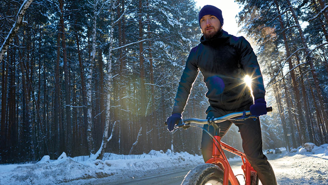 A man rides his fat tire bike down a snowy road