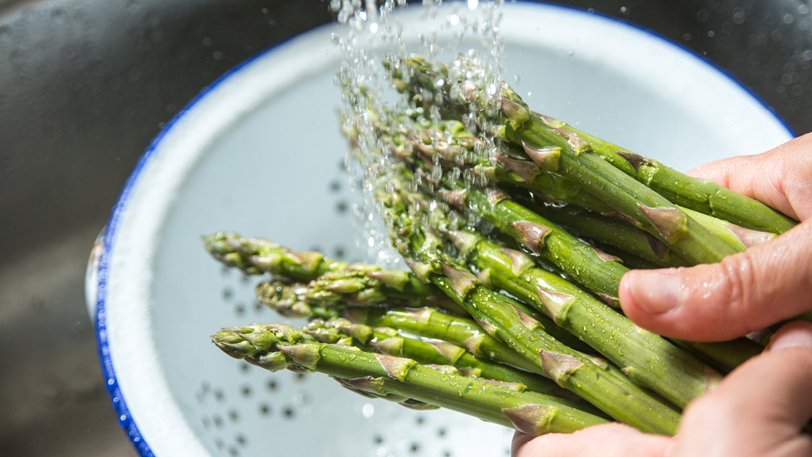 a person washing asparagus