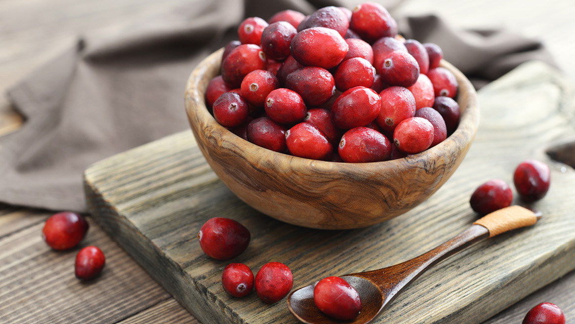 a wooden bowl with fresh, whole cranberries