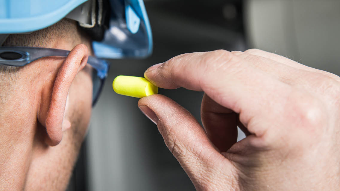a man wearing a construction hat putting a ear plug in