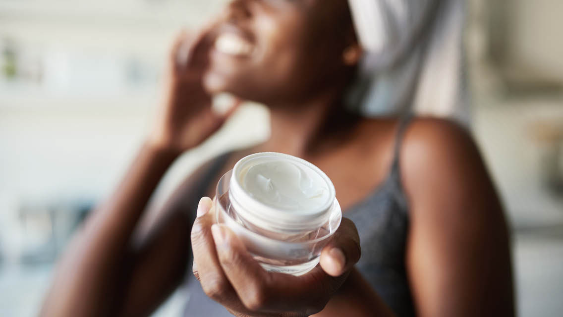 a woman shows a container of face lotion