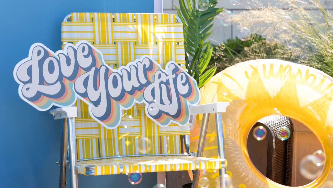 A pool chair and floaty with a sign that says "love your life".