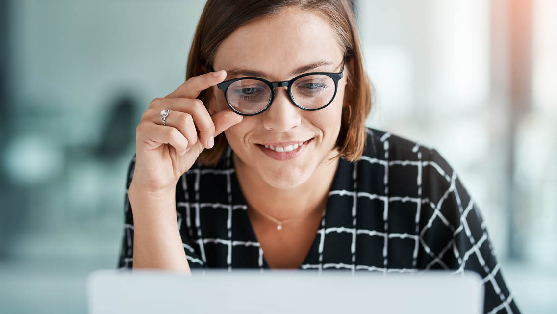 a woman wears glasses while looking at a computer