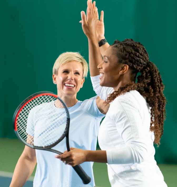 Two women high-fiving while playing tennis.