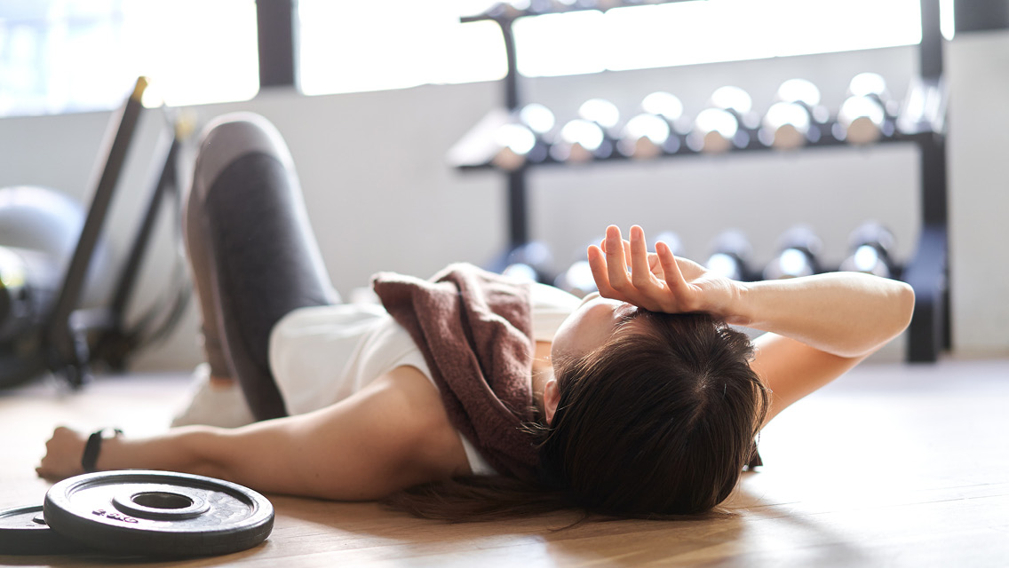 a person lies on a fitness center's floor in exhaustion