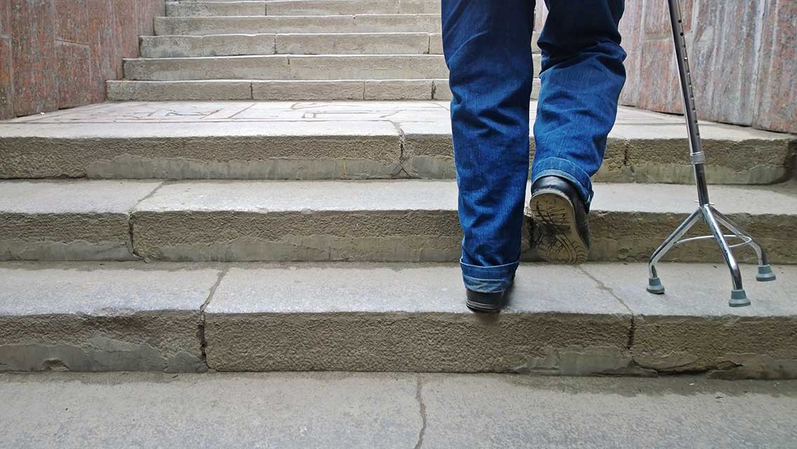 a man walks up a set of stone stairs with a cane