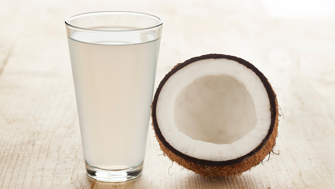 a class of coconut water and a sliced open coconut