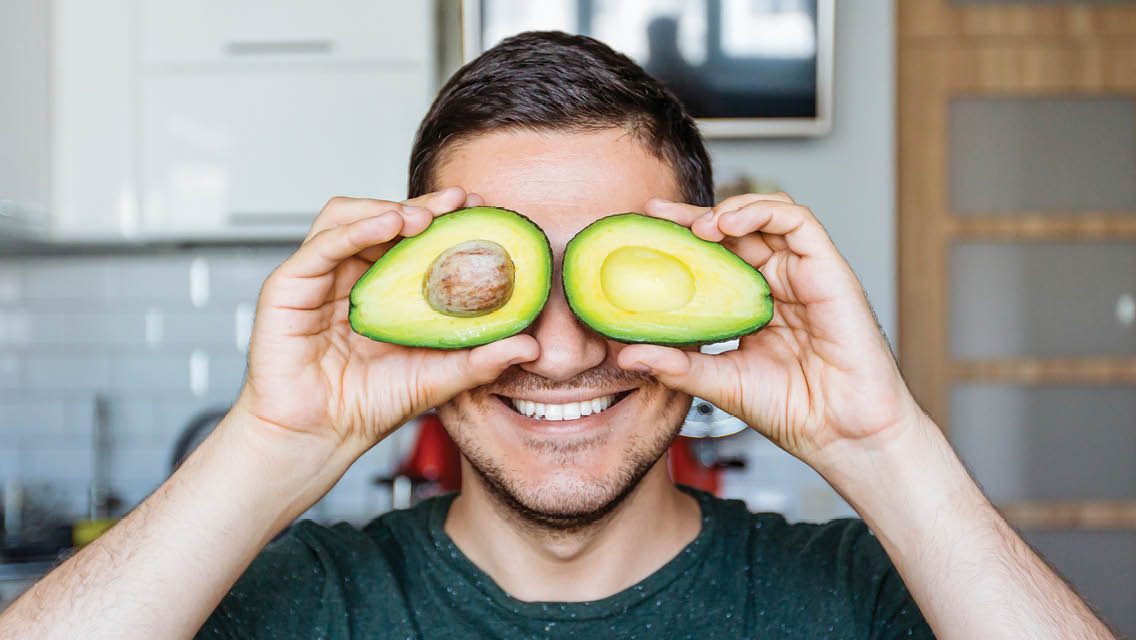 a man holds avocados over his eyes like a mask