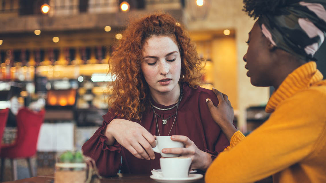 two women talk in a coffee shop