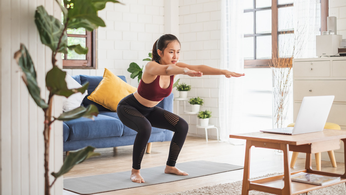 a woman holds a squat while working out in her living room