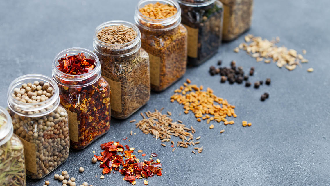 a row of glass spice jars filled with colorful spices