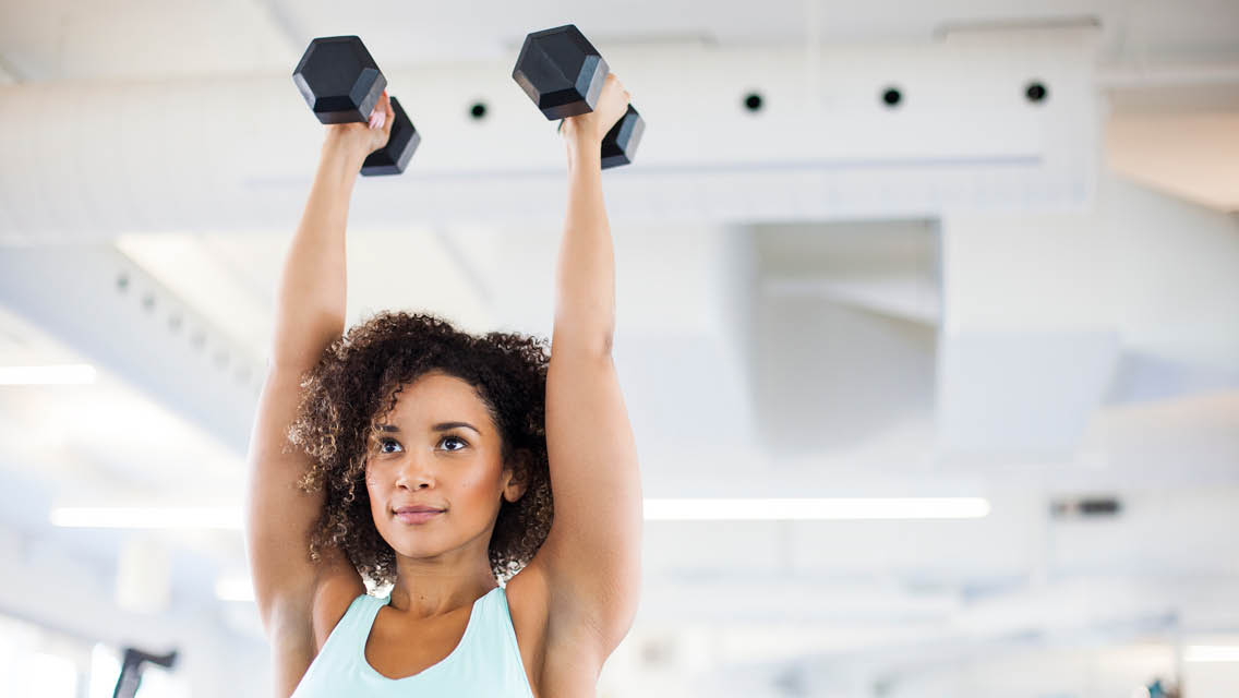 a woman holding dumbbells overhead