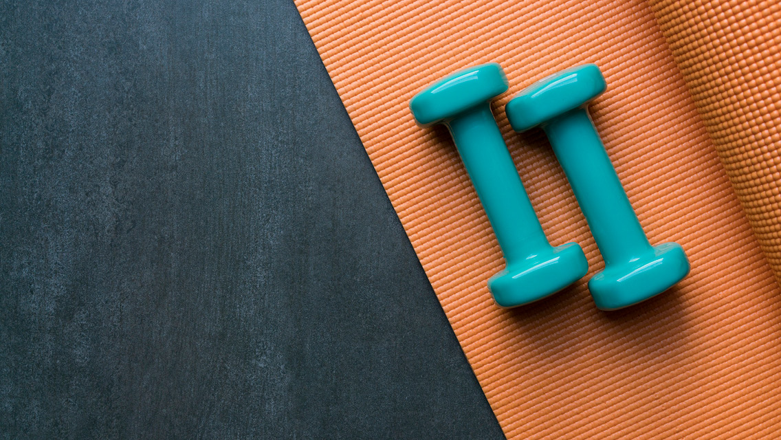 two light weight dumbbells sit on a yoga mat