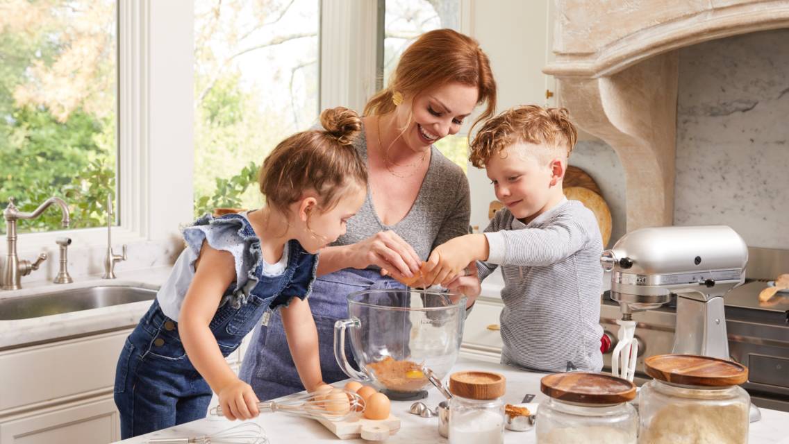 A woman and children baking together.