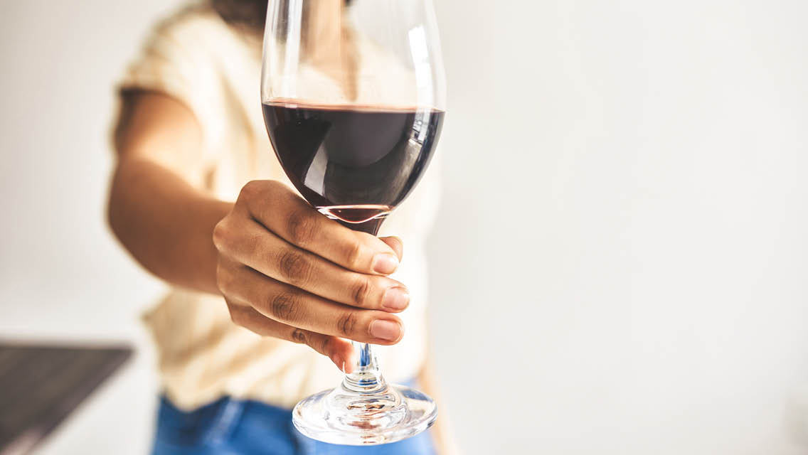a person holds a glass of red wine