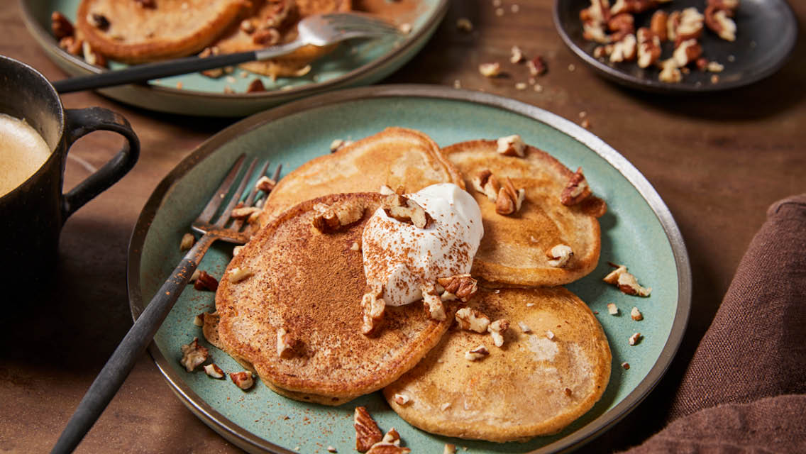 carrot cake pancakes topped with cream and pecans