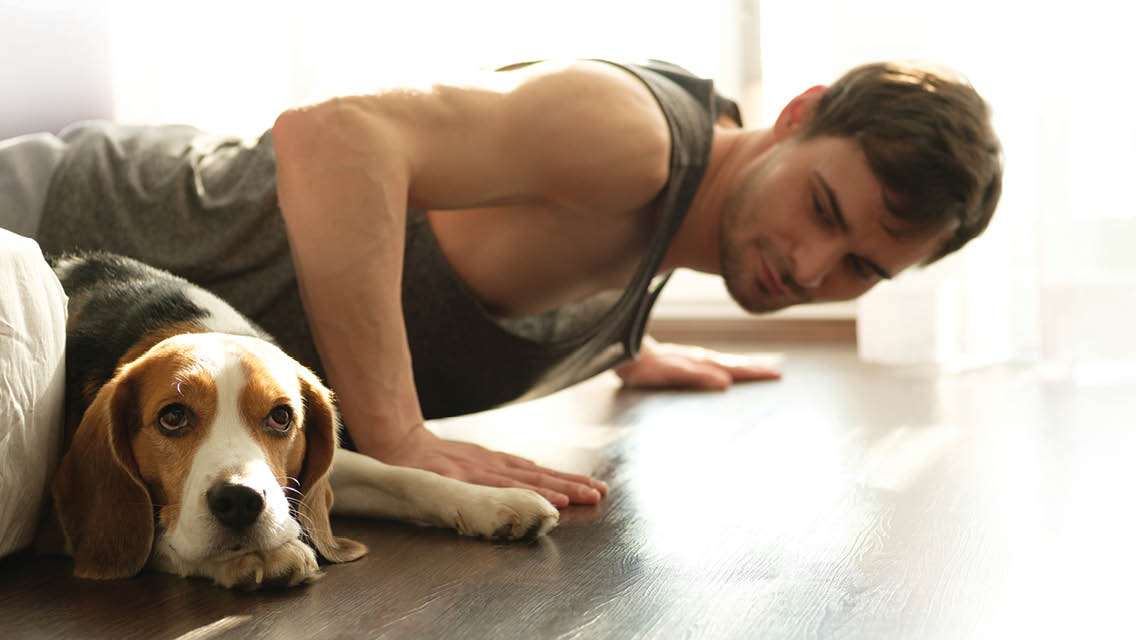 a man does a push up next to a lazy dog