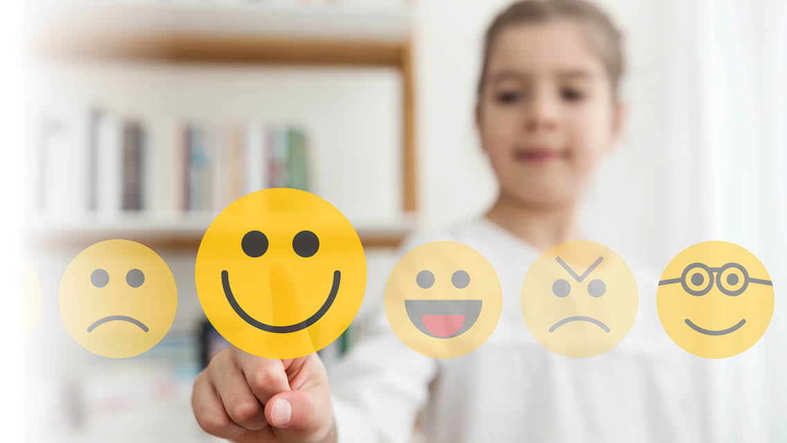 a young girl points to a smiling emojii