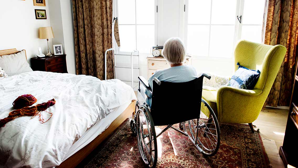 a woman sits in a chair in an assisted living apartment
