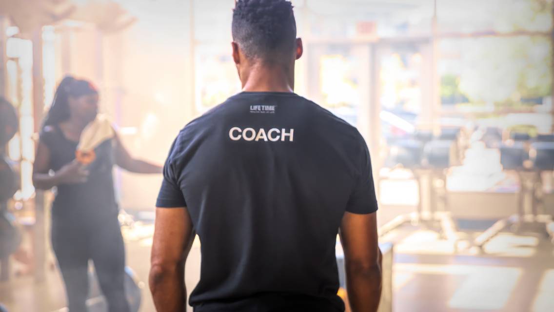 The back on a man's shirt that says "coach."