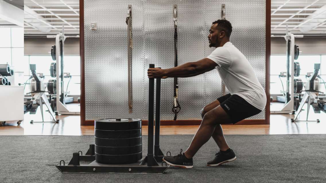 Shamik Perry pushing weights in a health club.
