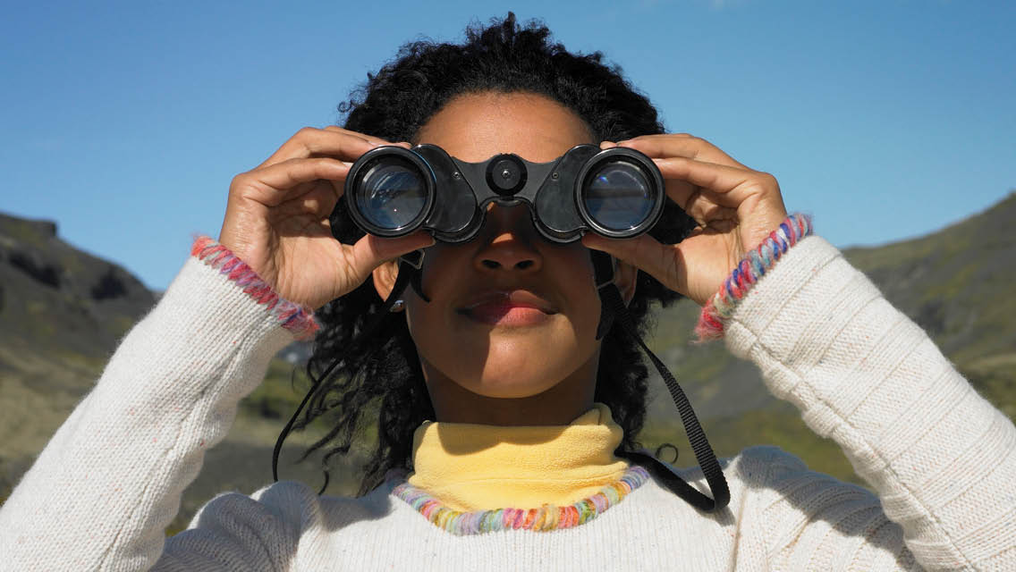a woman looks through binoculars