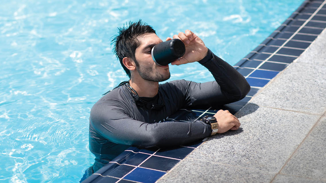 a man drinks a cup of water while in a pool