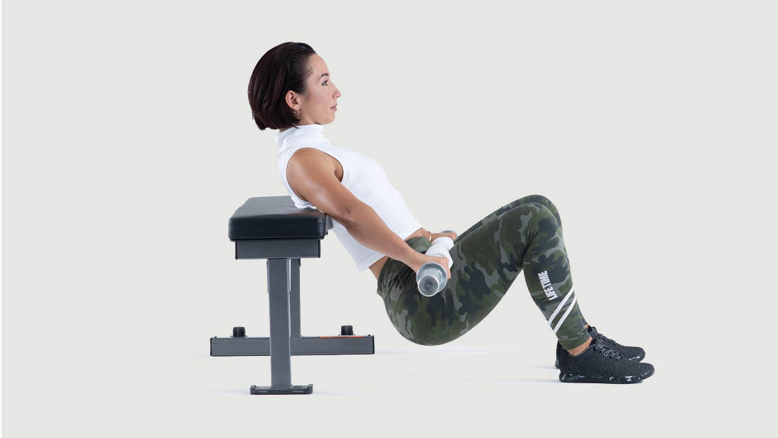 a woman performs a hip thrust using a bench