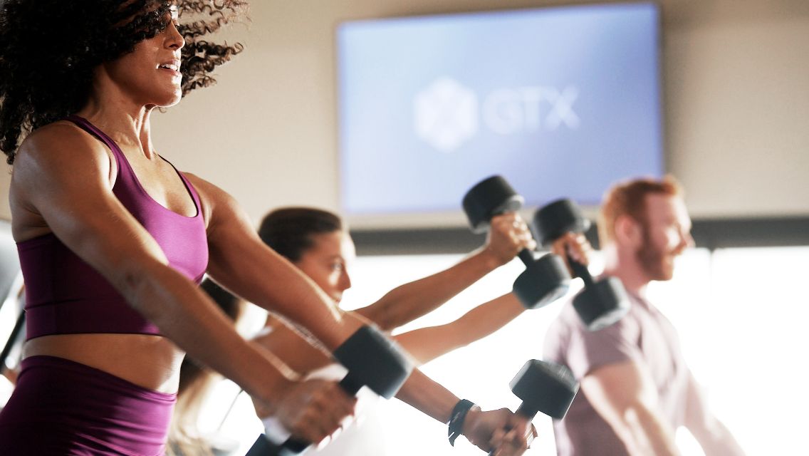Three people using dumbbells while exercising in a GTX class.