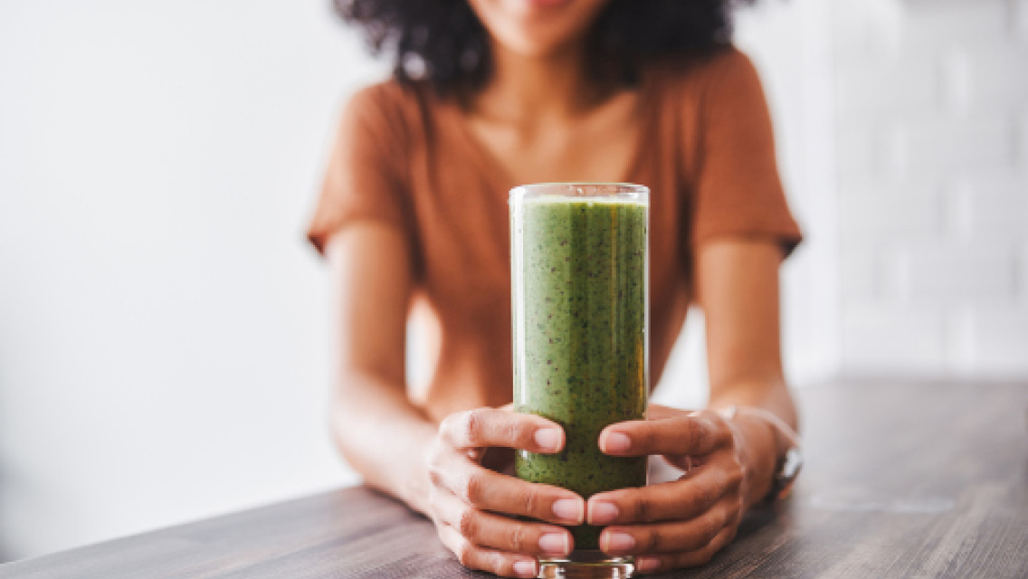 a woman holds a green smoothie