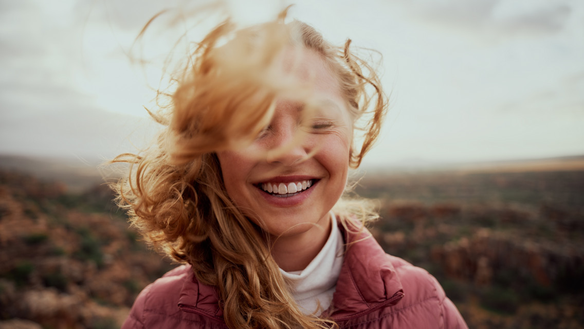 a smiling woman with hair being blown in the wind