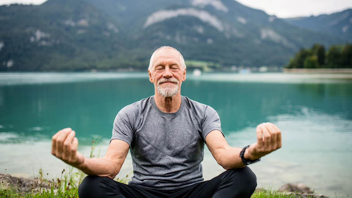 a man sits in nature doing yoga