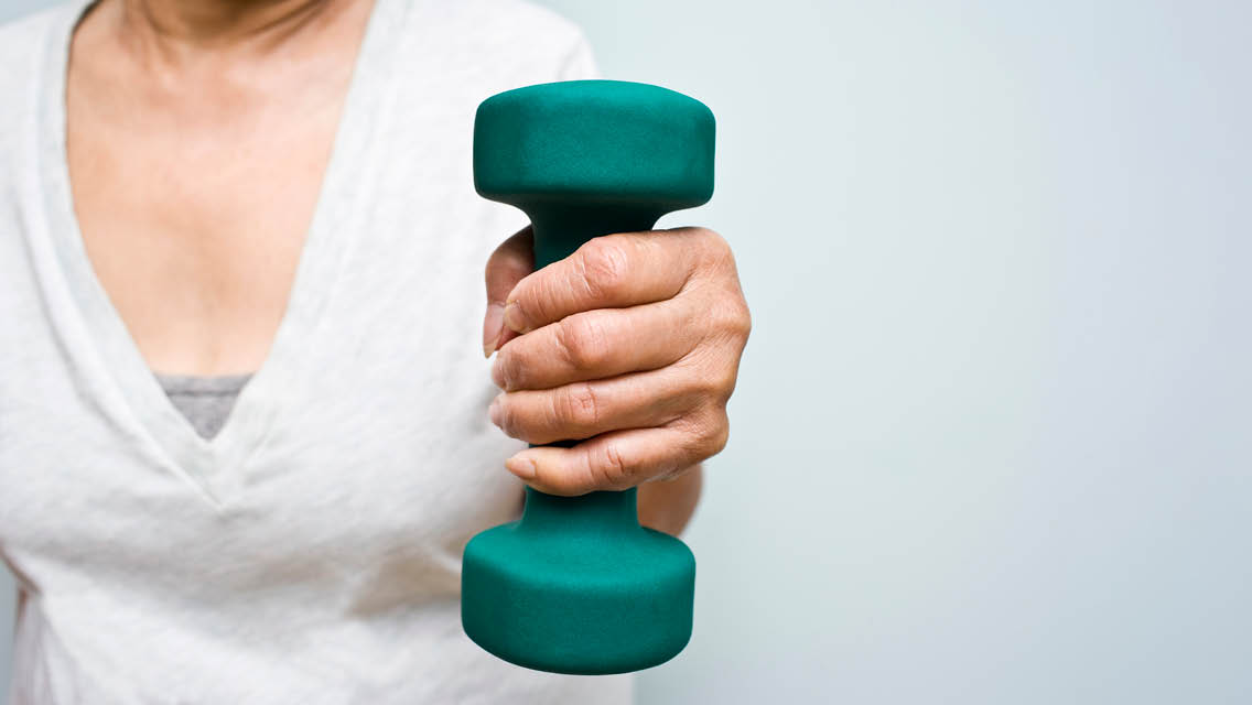 a woman holds a green dumbbell