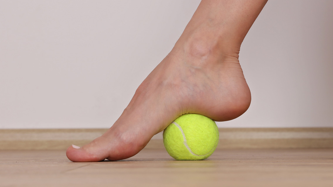 a foot rolling out on a tennis ball
