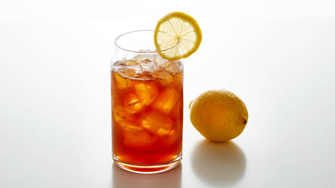 a tall glass of iced tea with a wedge of lemon